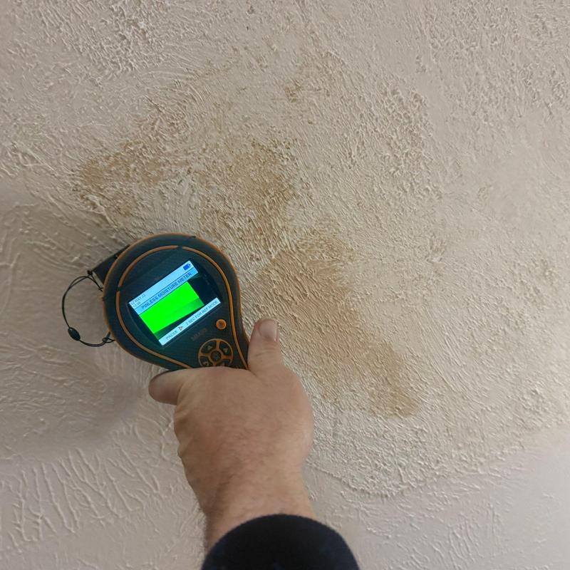 Drywall moisture meter detecting water damage stain