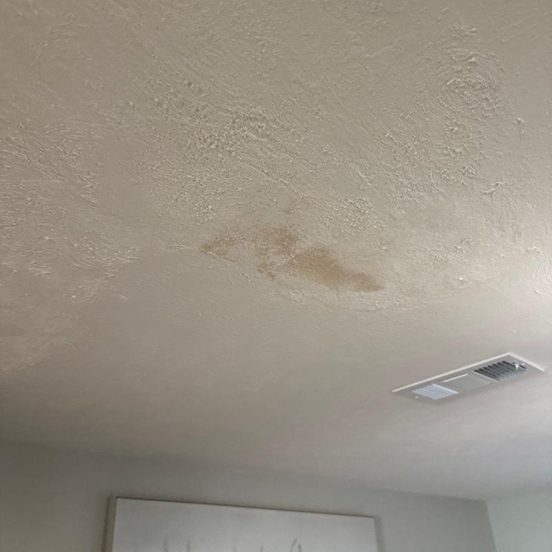 Ceiling water stain and textured plaster damage near vent