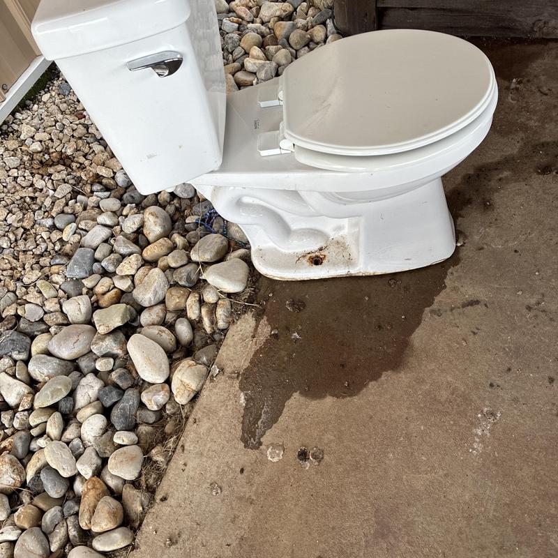 Toilet with water leak on concrete floor outdoors