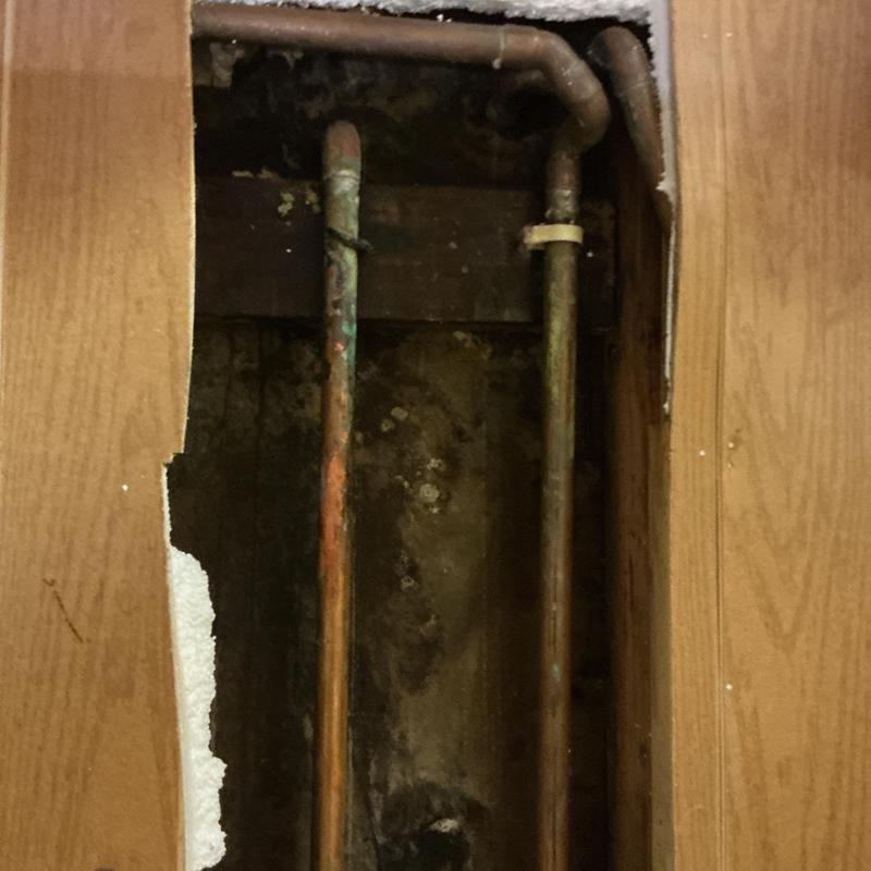 Copper water supply pipes behind cut drywall access panel
