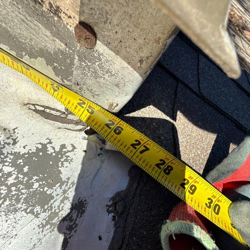 Metal roof flashing with measuring tape and hail damage