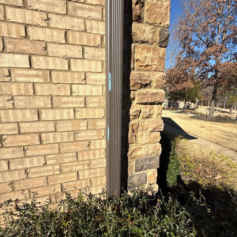 Downspout with marked hail damage on brick wall