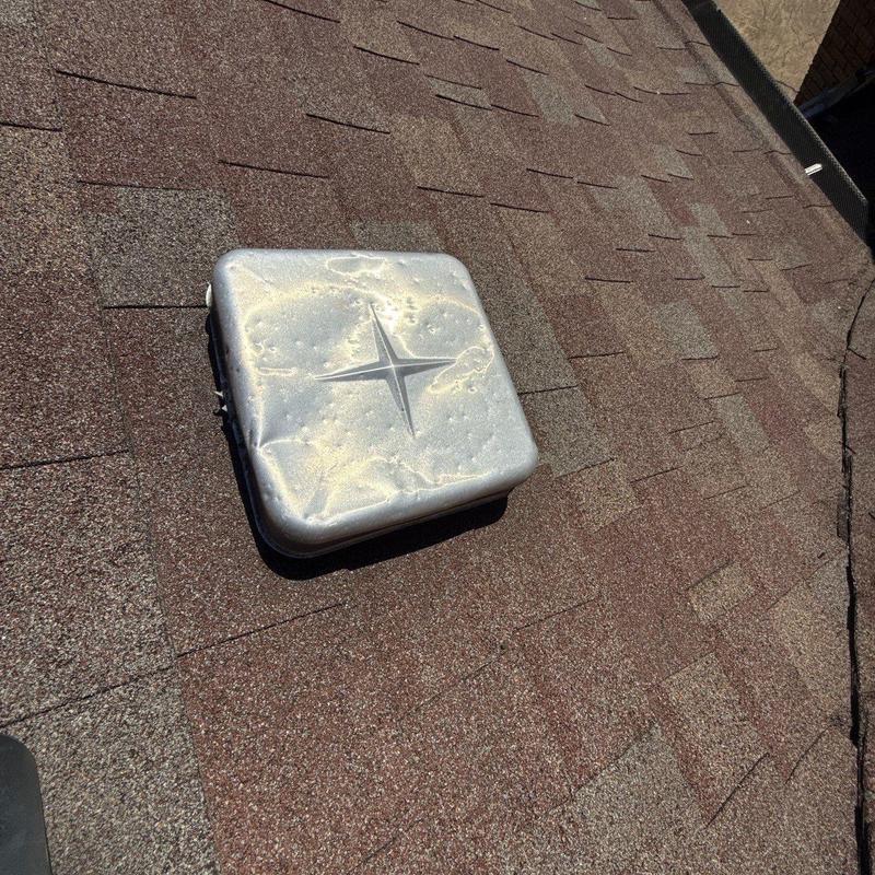 Roof vent cover with hail dents on asphalt shingles