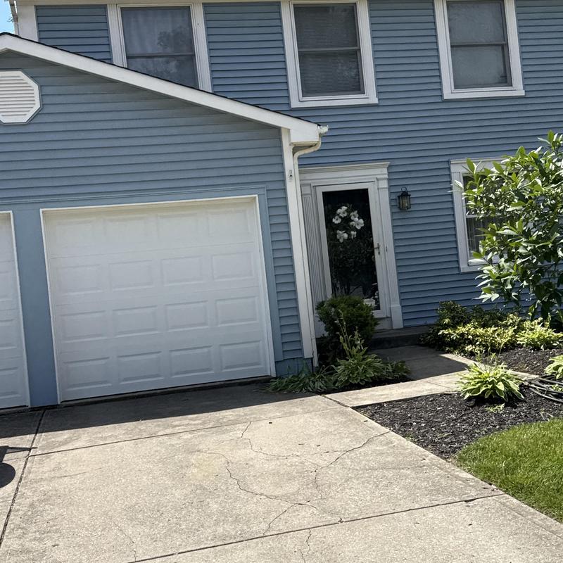 Concrete driveway with visible large cracks near garage door