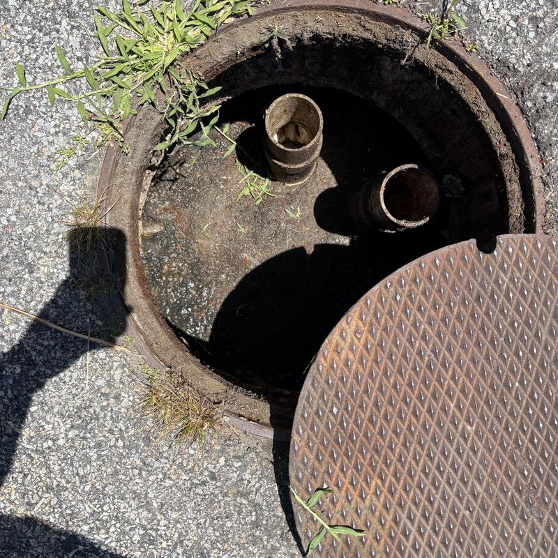 Sewer manhole with open cover and pipe vents Sewer manhole with open cover and pipe vents