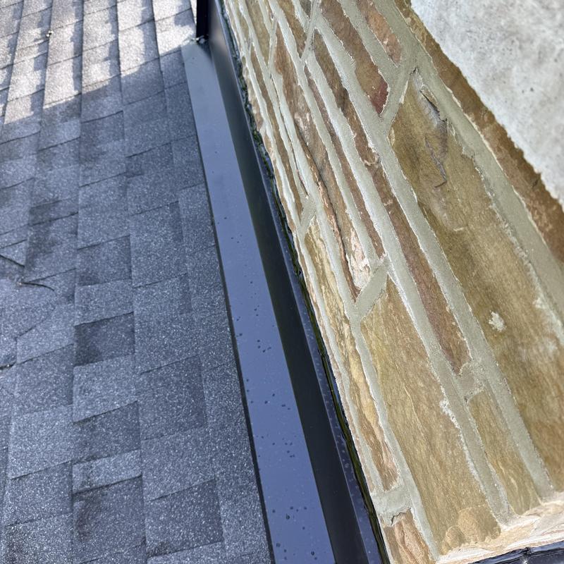 Roof flashing along brick wall with asphalt shingles Roof flashing along brick wall with asphalt shingles