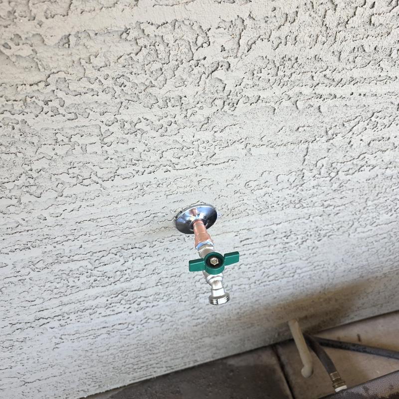 Hose bib with green handle on textured wall Hose bib with green handle on textured wall