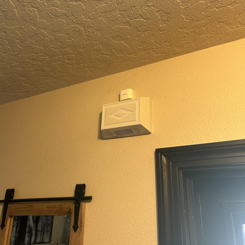 Doorbell chime unit on beige wall near door frame