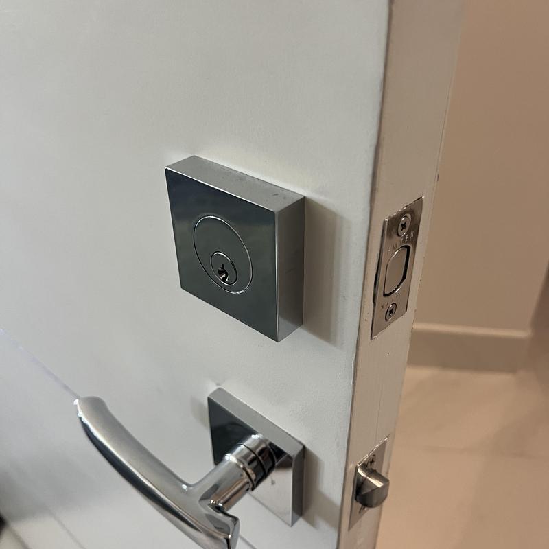 Square deadbolt lock and door handle on white door