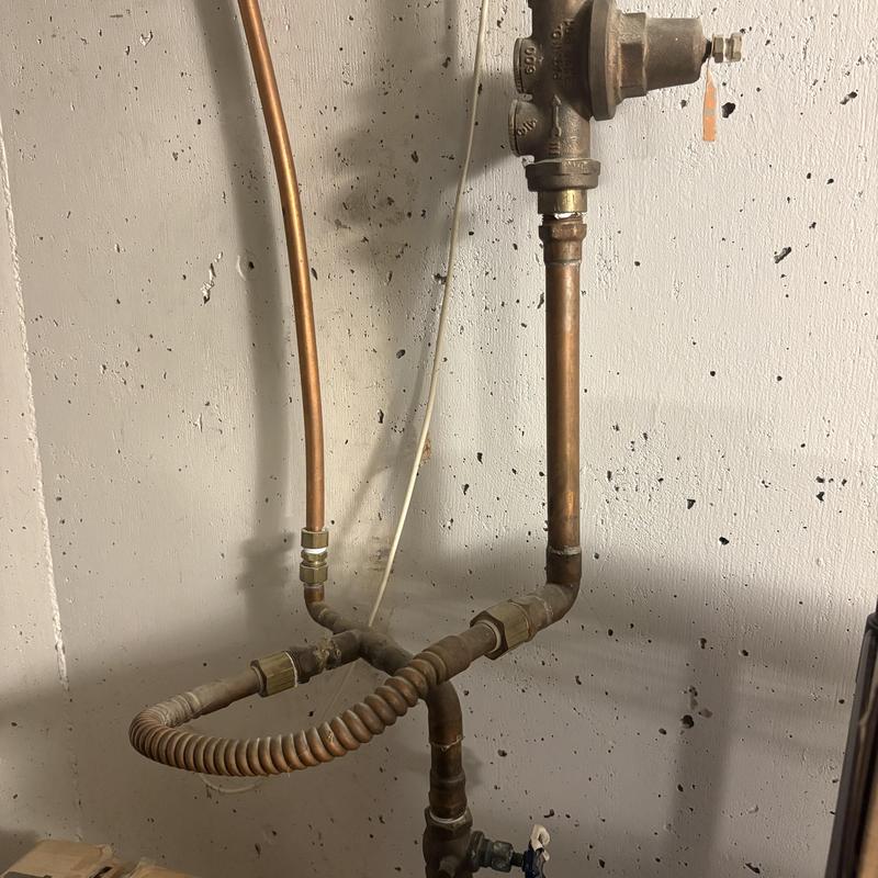 Gas line piping with flexible connector against concrete wall