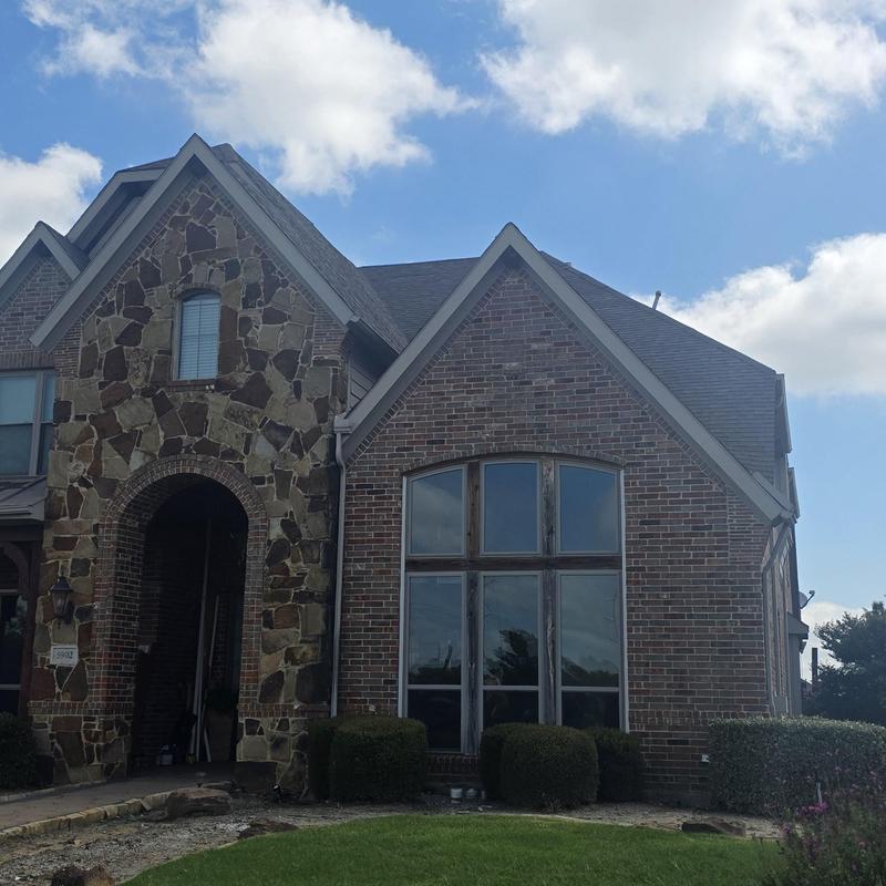Roof shingles with hail damage on brick house exterior