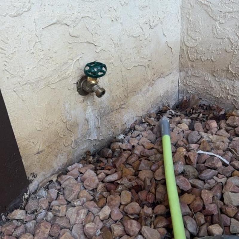 Exterior water spigot and garden hose on stone bed
