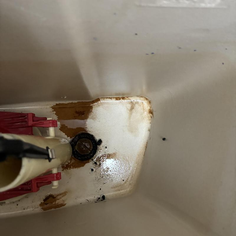 Toilet tank interior with fill valve and rust buildup