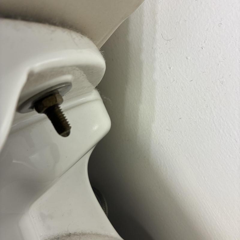 Toilet tank bolt and porcelain detail close-up