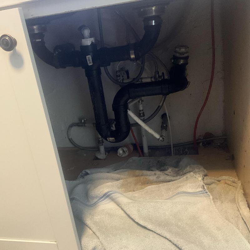 Kitchen sink drain pipes with towel on floor underneath Kitchen sink drain pipes with towel on floor underneath