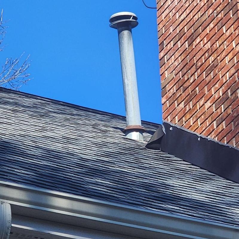 Heater pipe vent with rain collar on roof near chimney