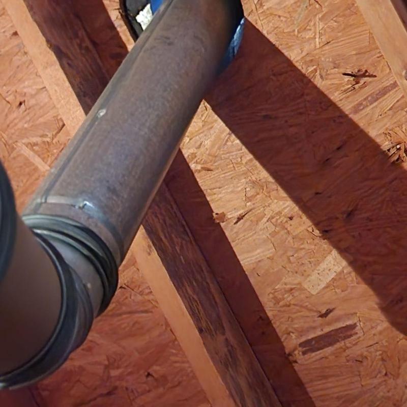 Heater pipe vent with rain collar in attic beams