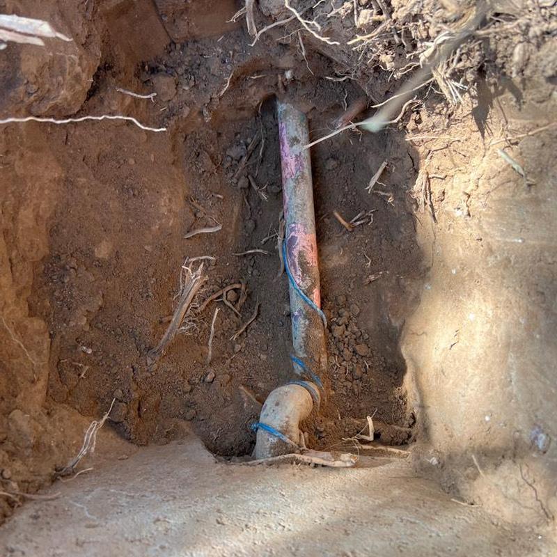 Water main excavated with 90-degree pipe fitting in soil