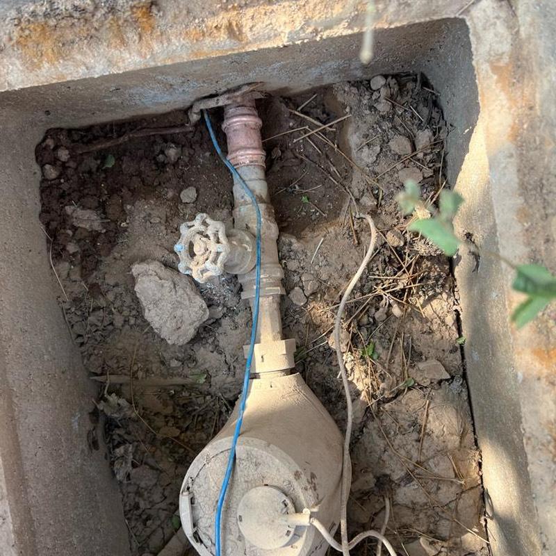 Water meter box with valve and piping in soil.
