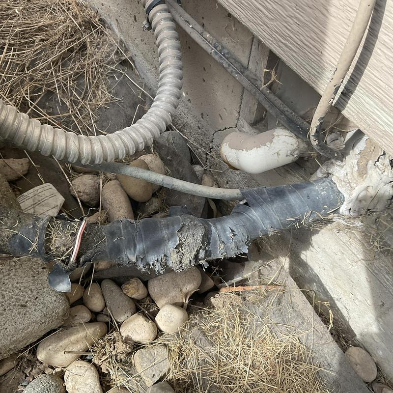 HVAC refrigerant line with damaged insulation outdoors