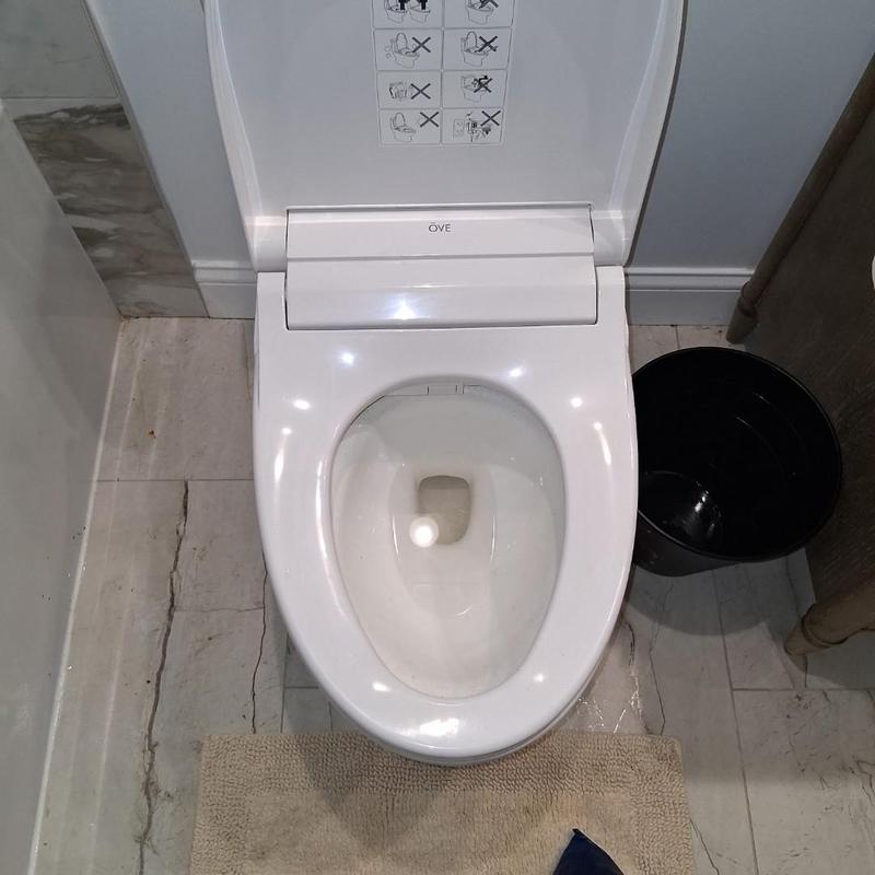 Smart toilet bowl with open lid and bucket nearby