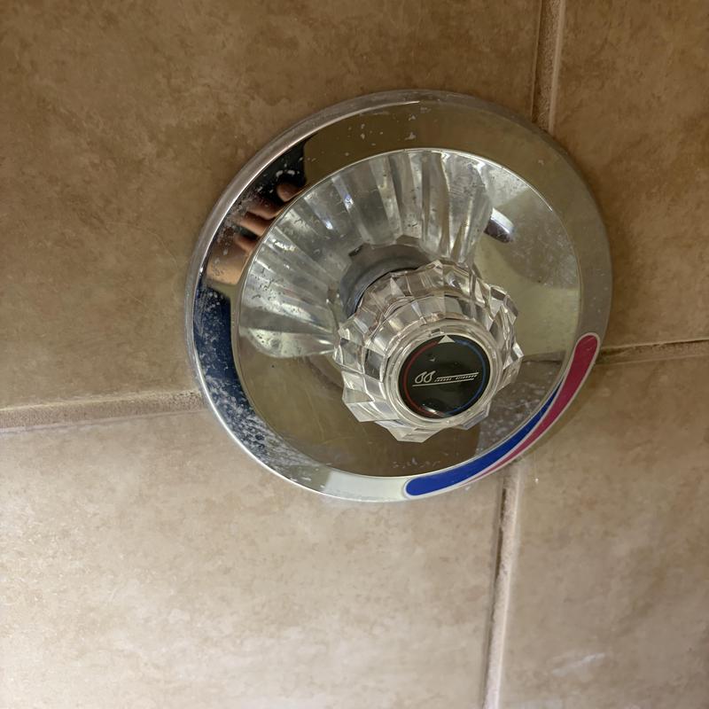 Shower temperature control knob and trim plate on tile wall