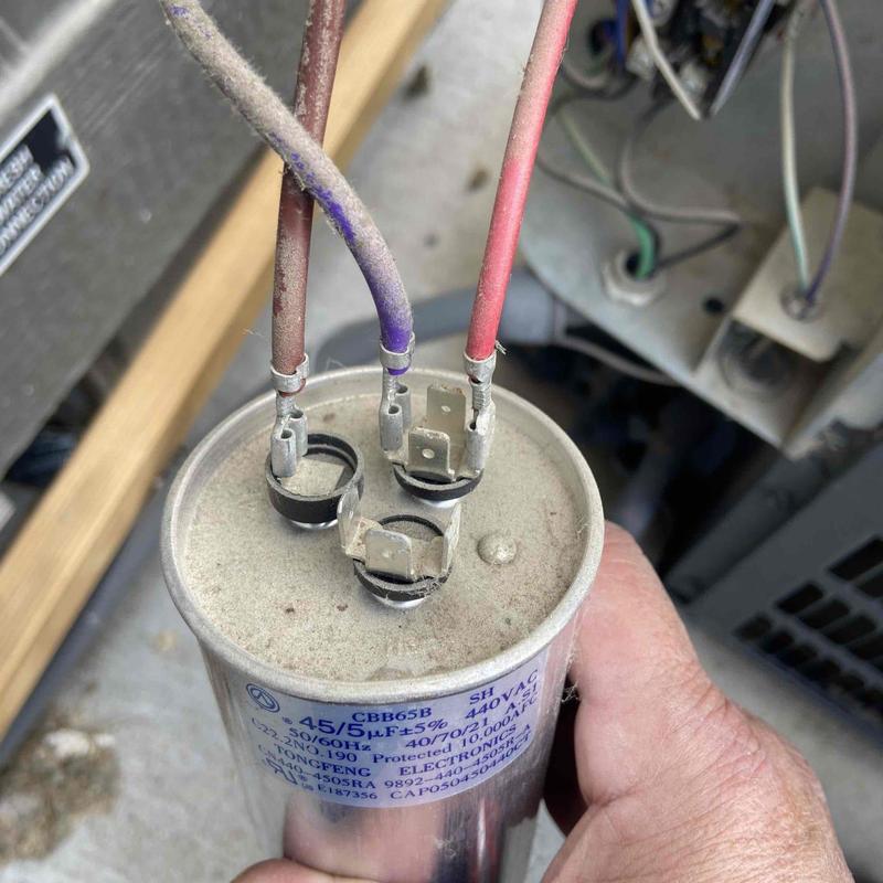 HVAC capacitor with electrical wiring in hand