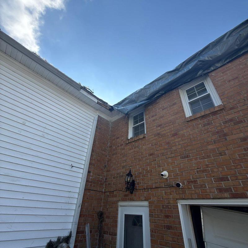 Roof edge with hail damage and protective tarp installed