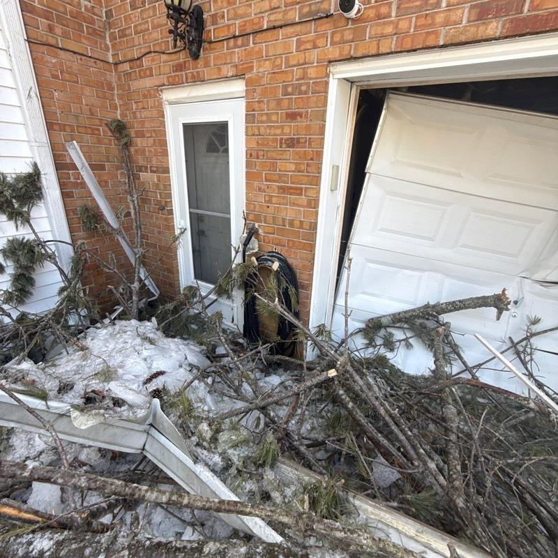 Garage door damaged by fallen tree branches and ice.
