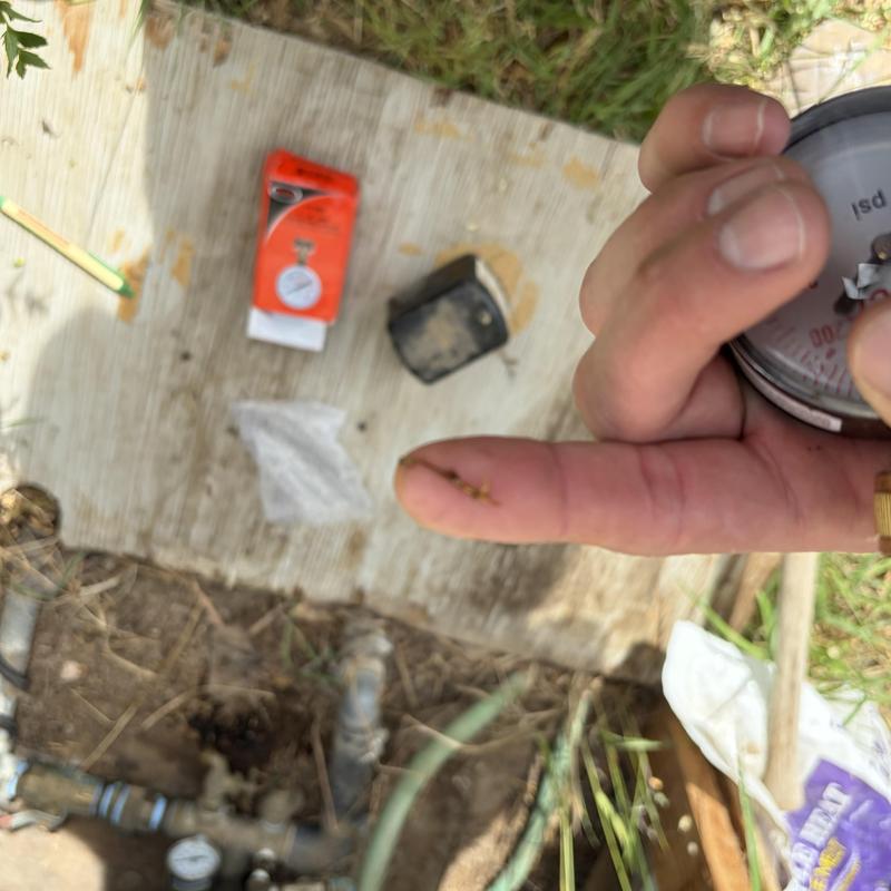 Well pressure gauge held showing debris on finger at well site Well pressure gauge held showing debris on finger at well site