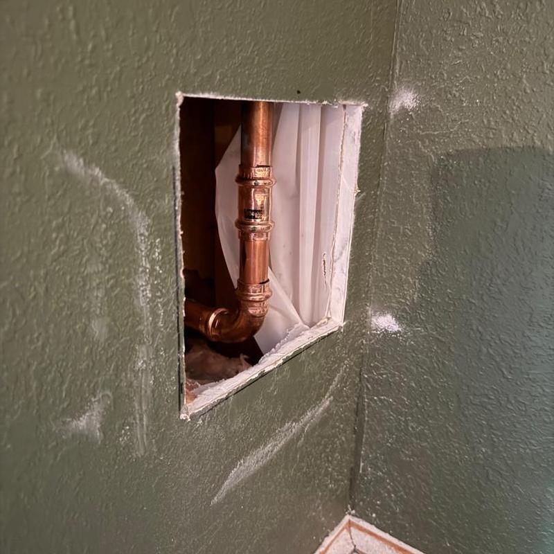 Copper plumbing pipes inside cut drywall wall