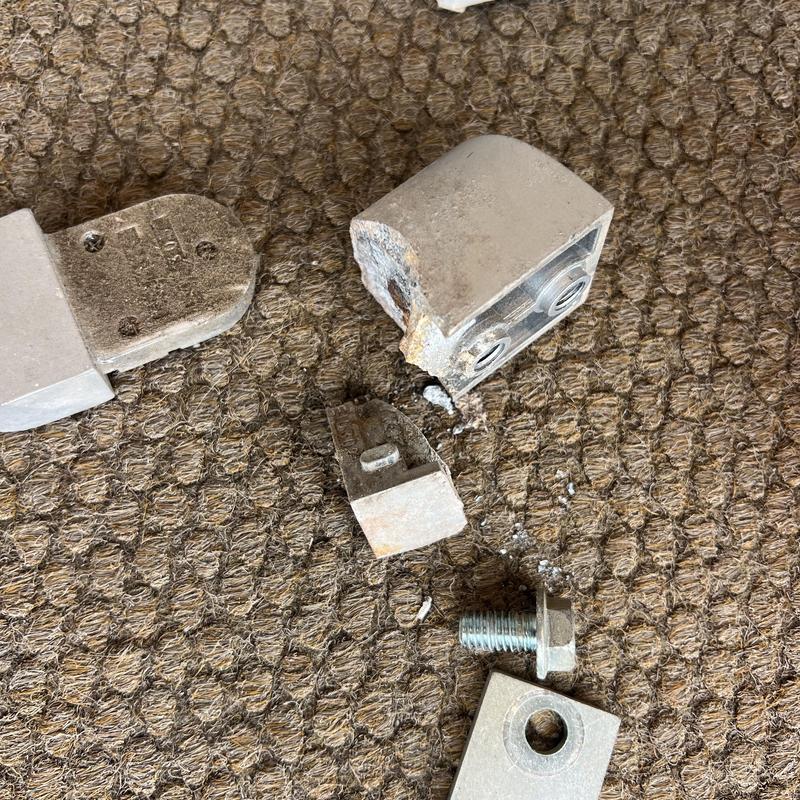 Broken lower door pivot with hardware on floor