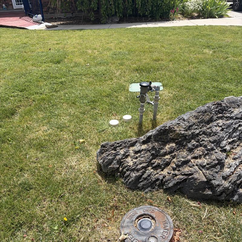 Water meter and valve assembly in yard near rock Water meter and valve assembly in yard near rock
