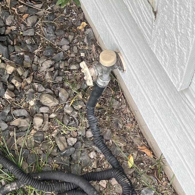 Hosebib with attached garden hose outside house Hosebib with attached garden hose outside house