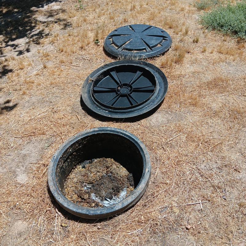 Septic tank access lids open in dry yard soil