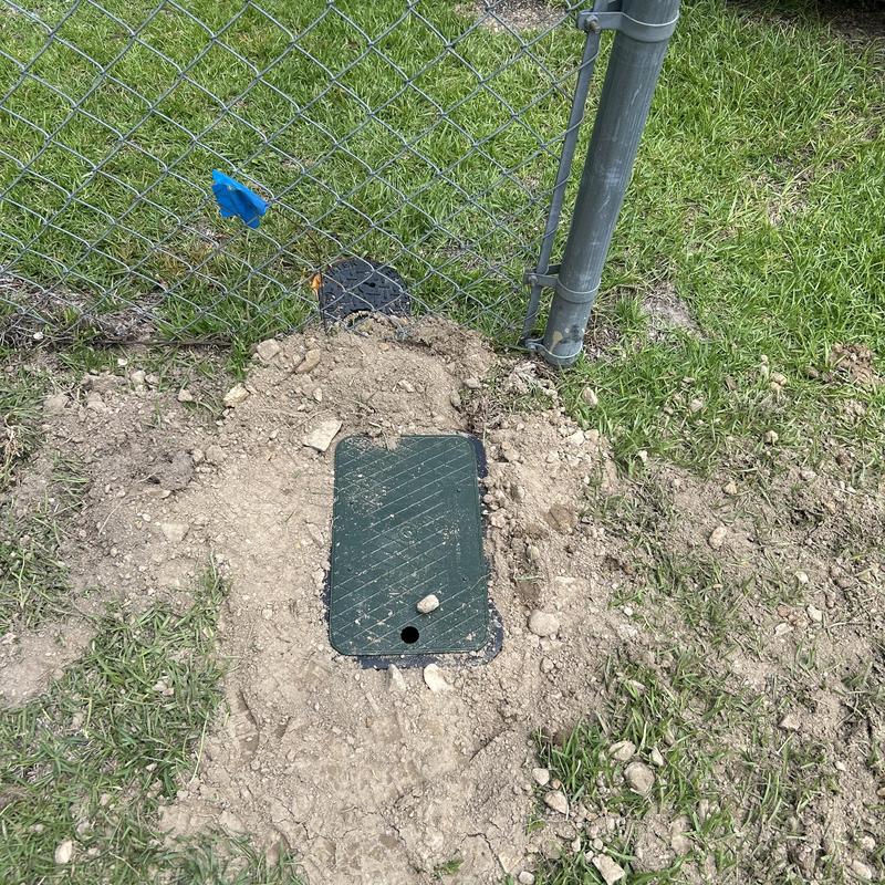 Water service pipe valve box next to fence post Water service pipe valve box next to fence post