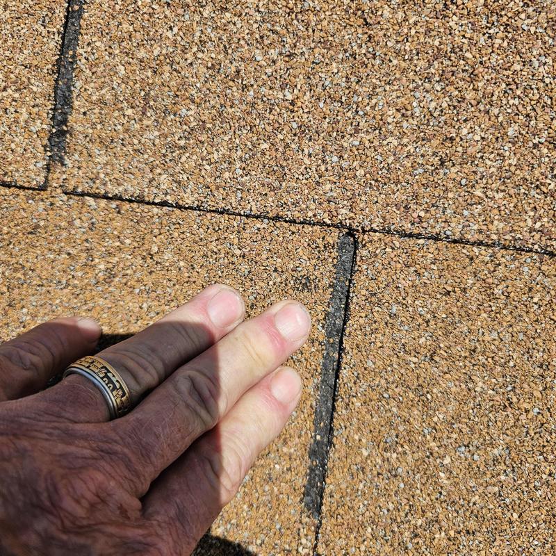 Asphalt roof shingles showing wind and hail damage close-up