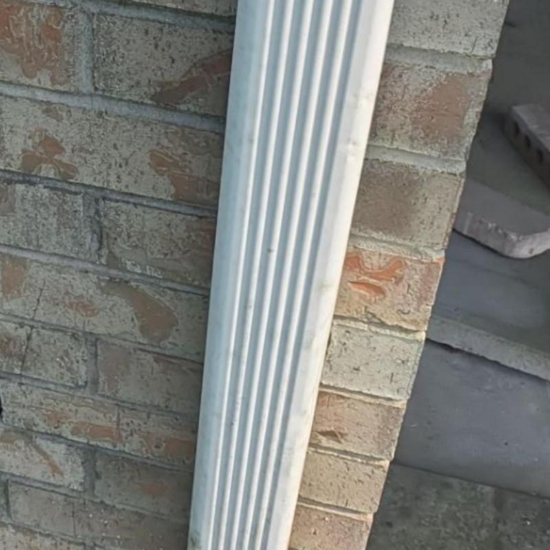 Gutter downspout on brick exterior wall with wear marks
