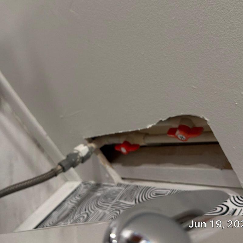 Water supply pipes with red valve handles behind wall panel Water supply pipes with red valve handles behind wall panel