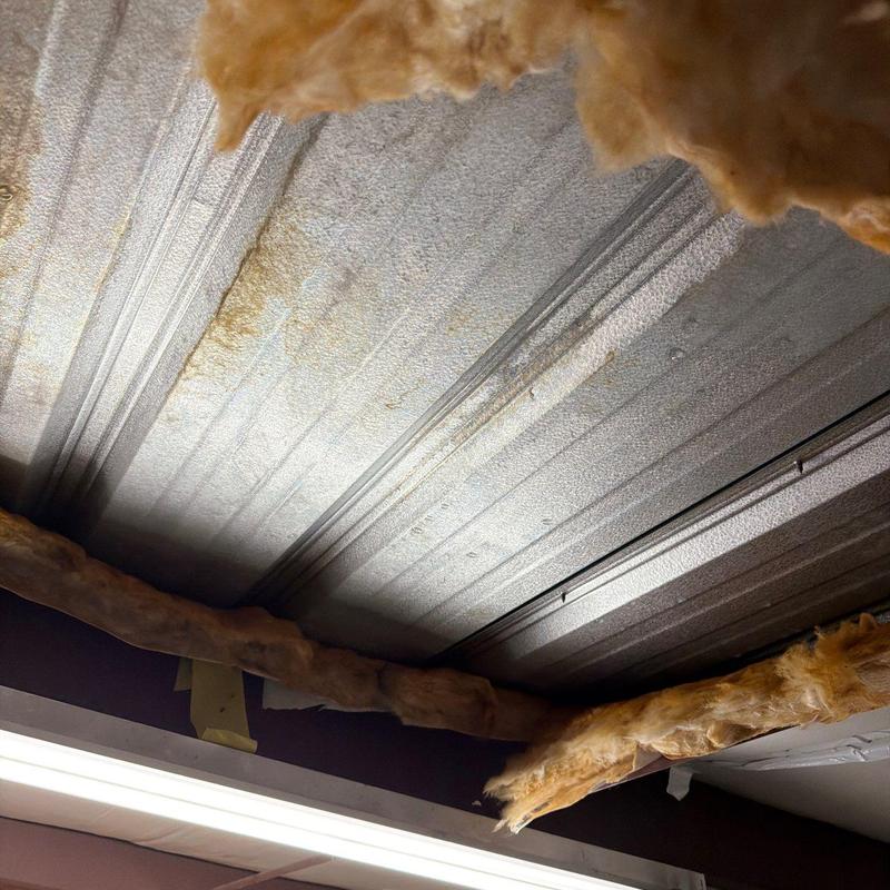 Metal roofing panel with insulation damage and rust spots