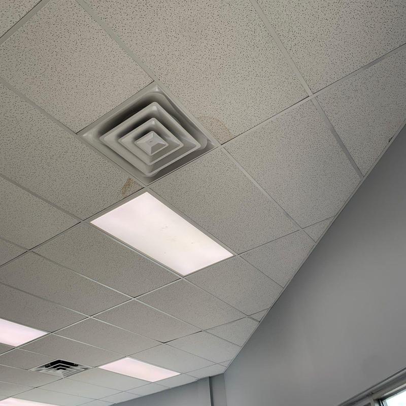 Drop ceiling tiles with water stains near vent and lights