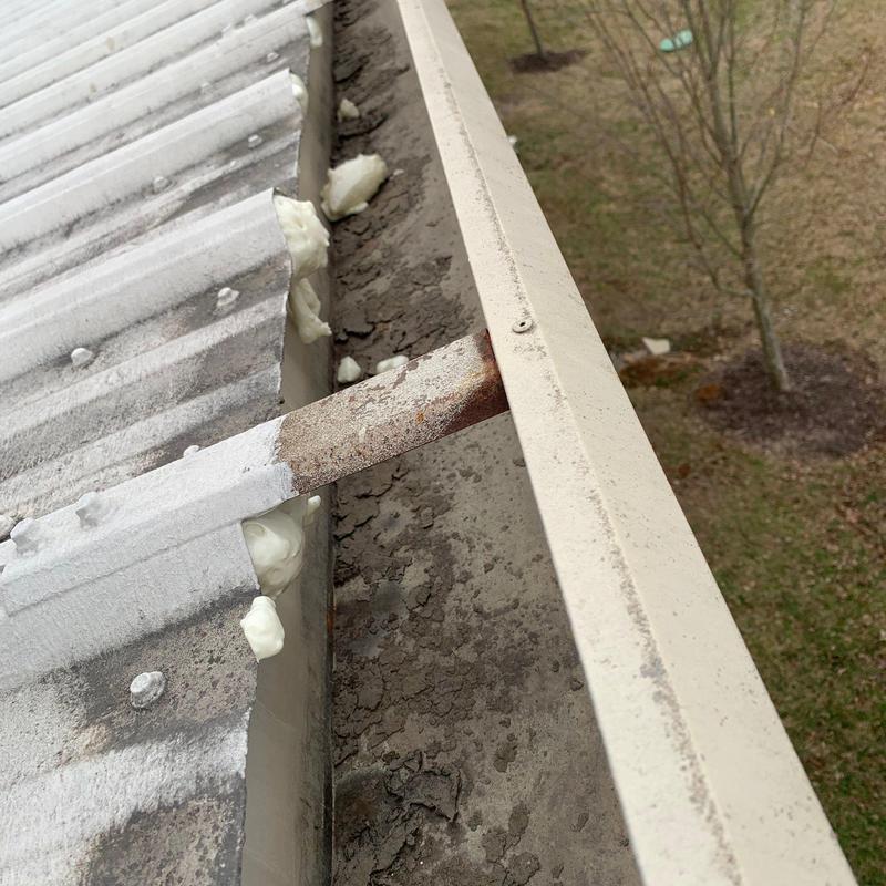 Metal roof edge with rusted support brace and sealant foam