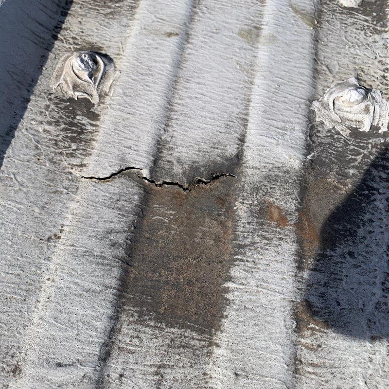 Commercial metal roof with crack and hail damage