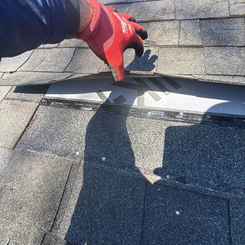 Roof shingles lifted to inspect underlying flashing damage