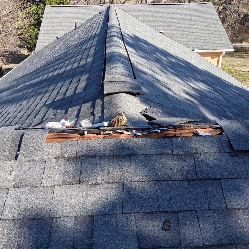Roof ridge shingles damaged with exposed wood framing