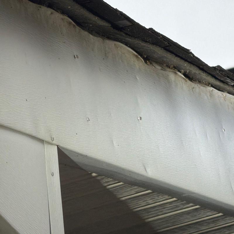 Fascia board with water damage and worn roof shingles