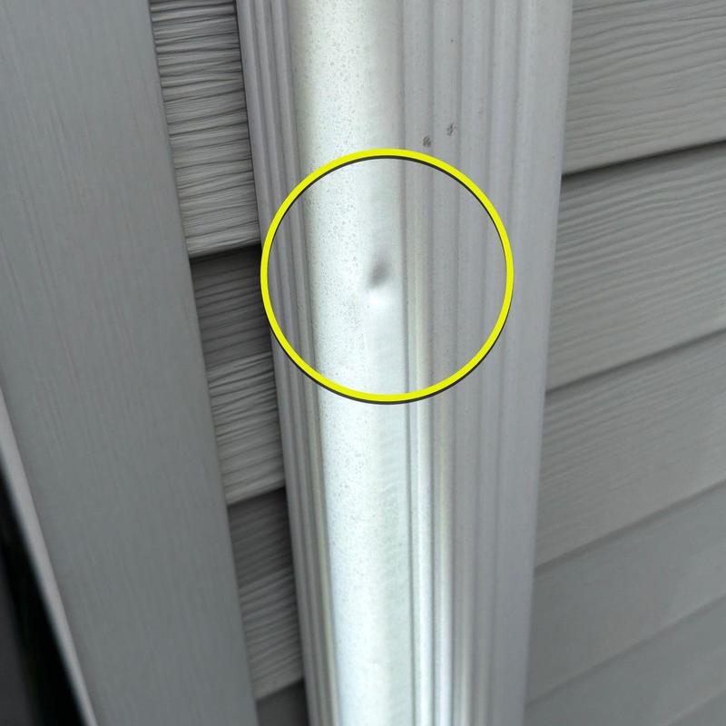 Metal gutter dent with yellow inspection circle