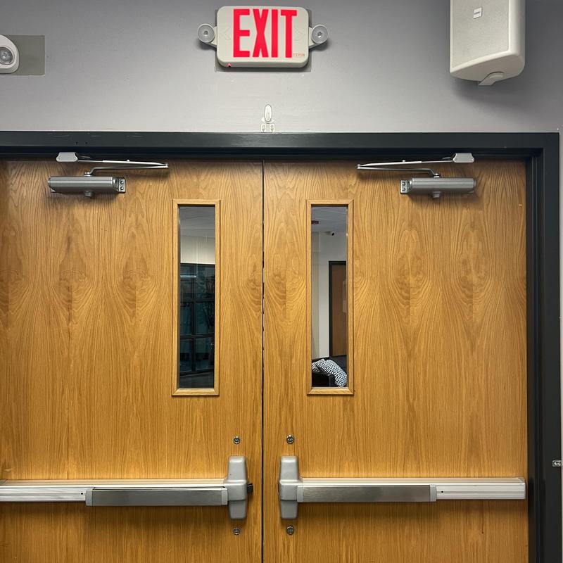 Door closers installed on double wooden exit doors