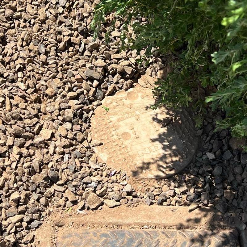 Pressure-reducing valve box surrounded by gravel and shrubbery