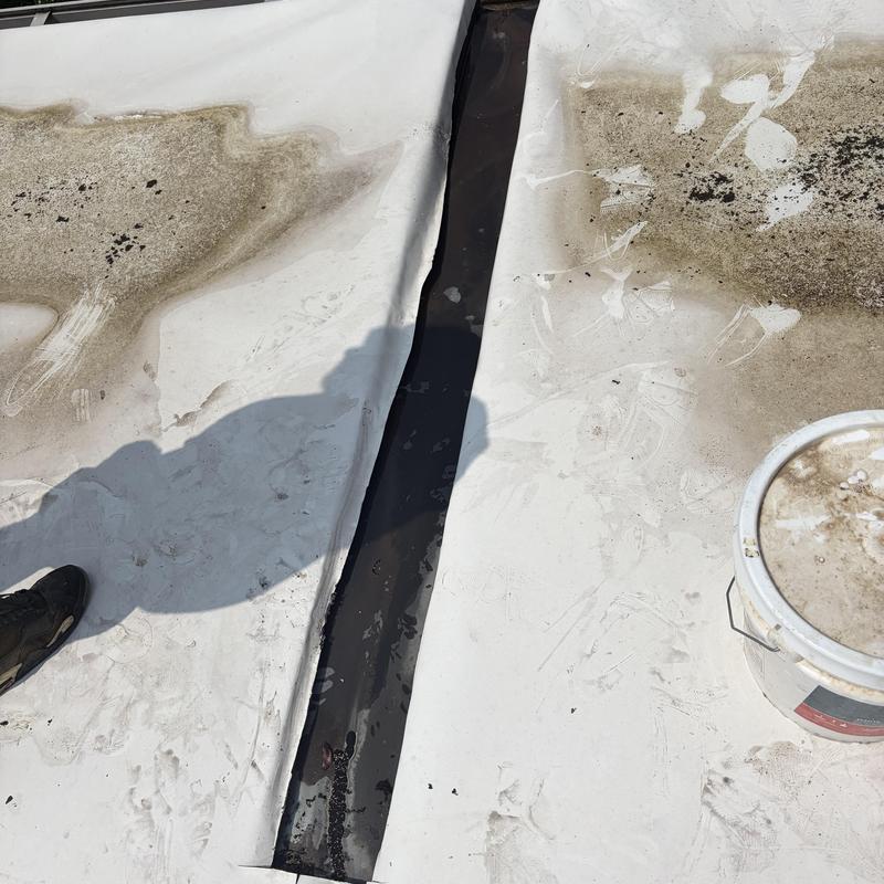 Flat roof membrane seam with dirt and inspection bucket